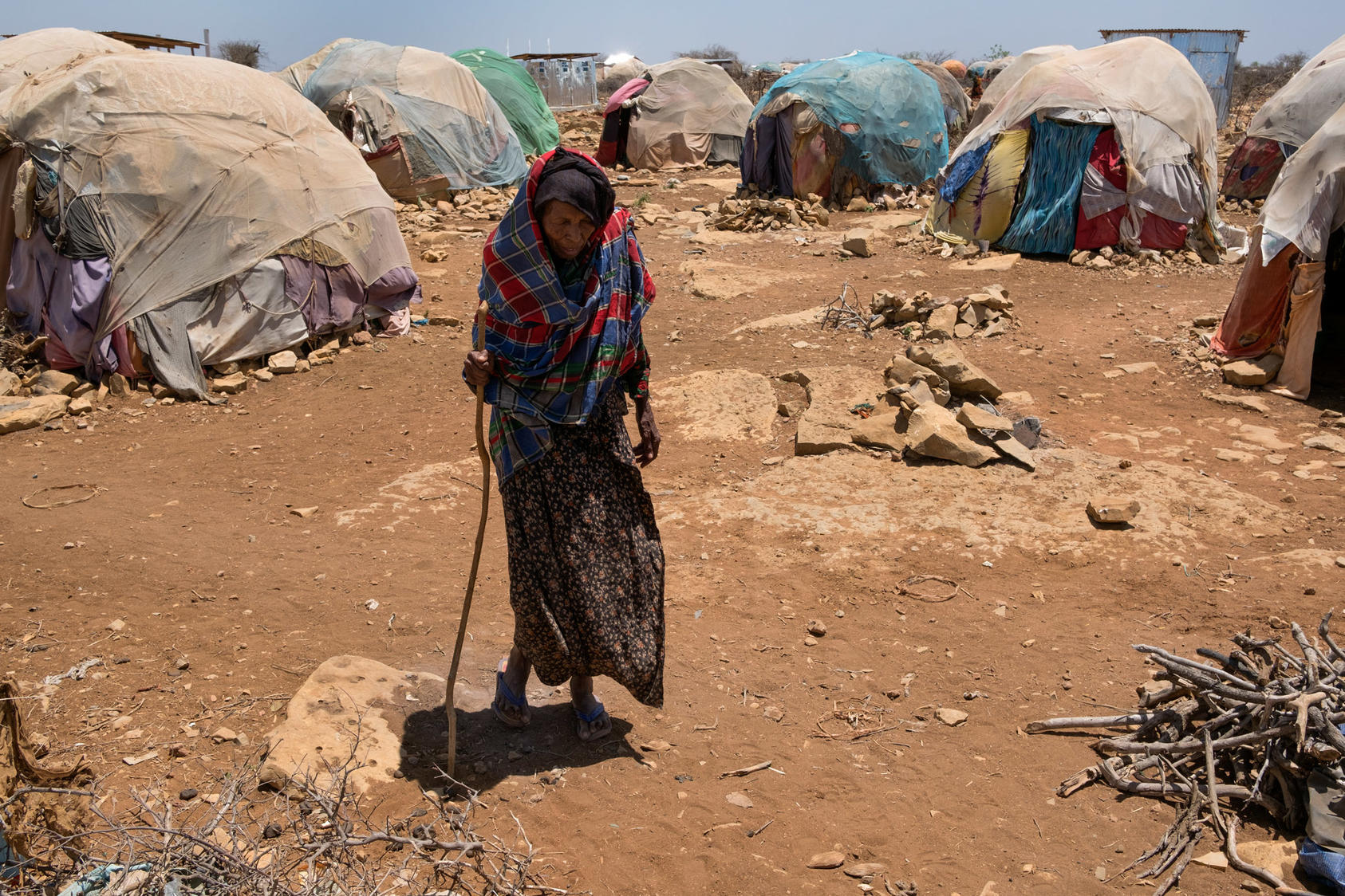 An elderly woman, displaced by the drought in Somalia, walks between makeshift tents at a camp in Baidoa, March 9, 2017.