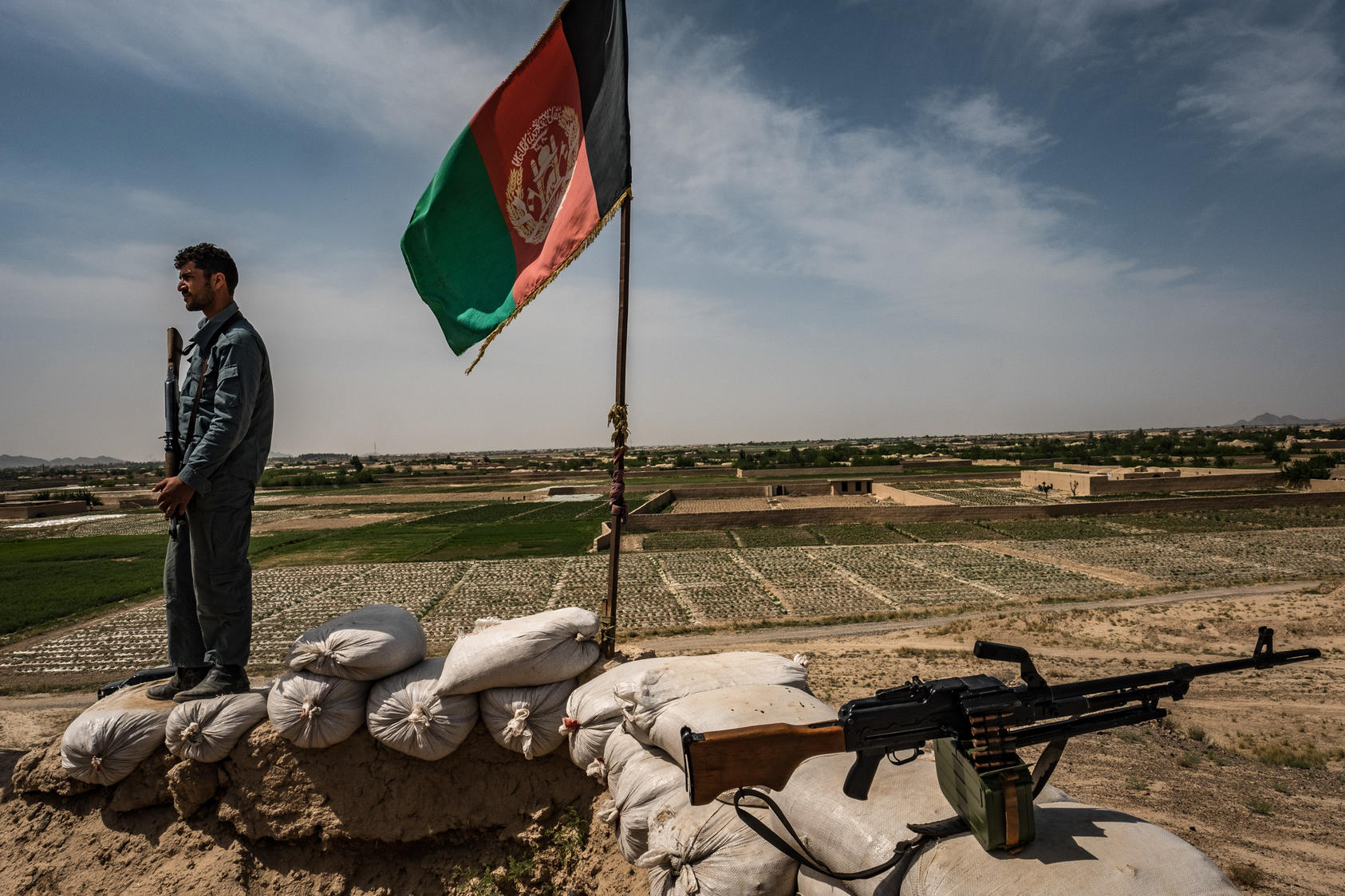 An Afghan policeman stands watch at his unit’s small hilltop outpost overlooking the districts north of the provincial capital of Farah in Afghanistan, April 2017. Photo Courtesy of The New York Times/Bryan Denton