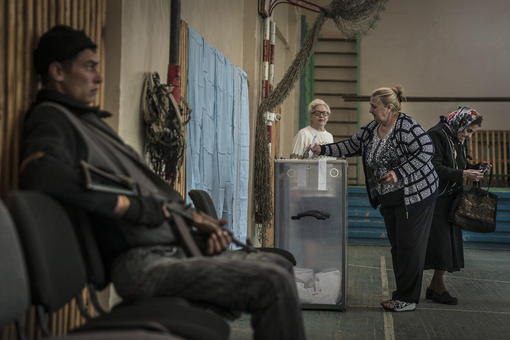 Residents cast their ballots on the autonomy referendum as a rebel fighter guards the polling station in Slovyansk, Ukraine, May 11, 2014. A steady stream of voters turned out at several polling stations on Sunday for snap elections intended to legitimize two self-declared new countries in eastern Ukraine, a showing that will aid the secessionist cause. (Sergey Ponomarev/The New York Times)