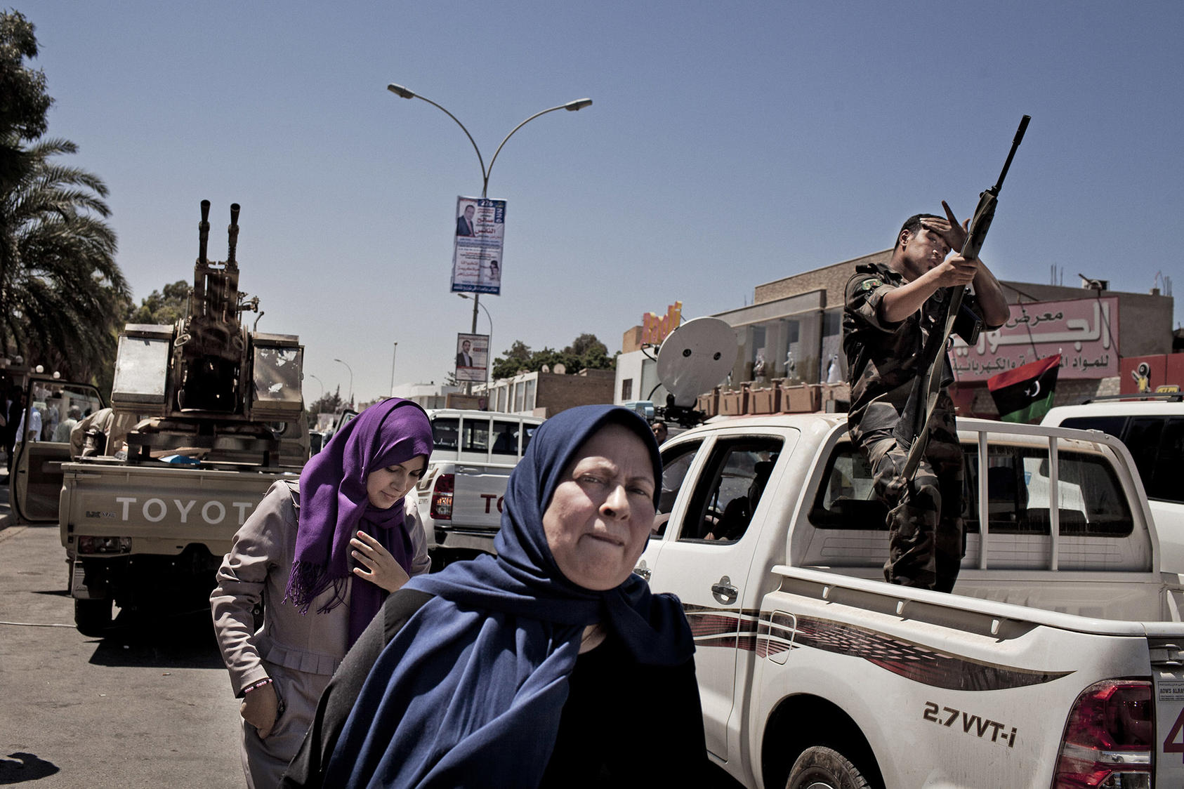 Women in Benghazi pass armed police and soldiers in a city street. Urban women include civic activists, and rural women include traditional tribal mediators, who work to halt fighting. (Tomas Munita/The New York Times)