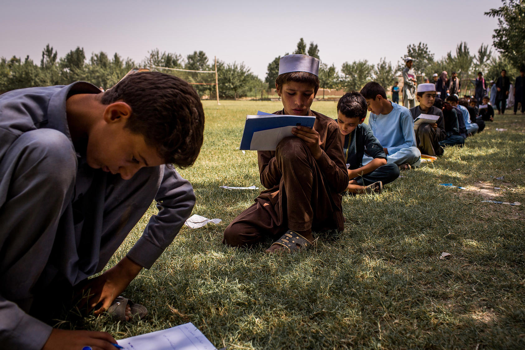 Students take an exam outdoors because their school had suffered extensive damage in fighting between Taliban and government forces. (Jim Huylebroek/New York Times)
