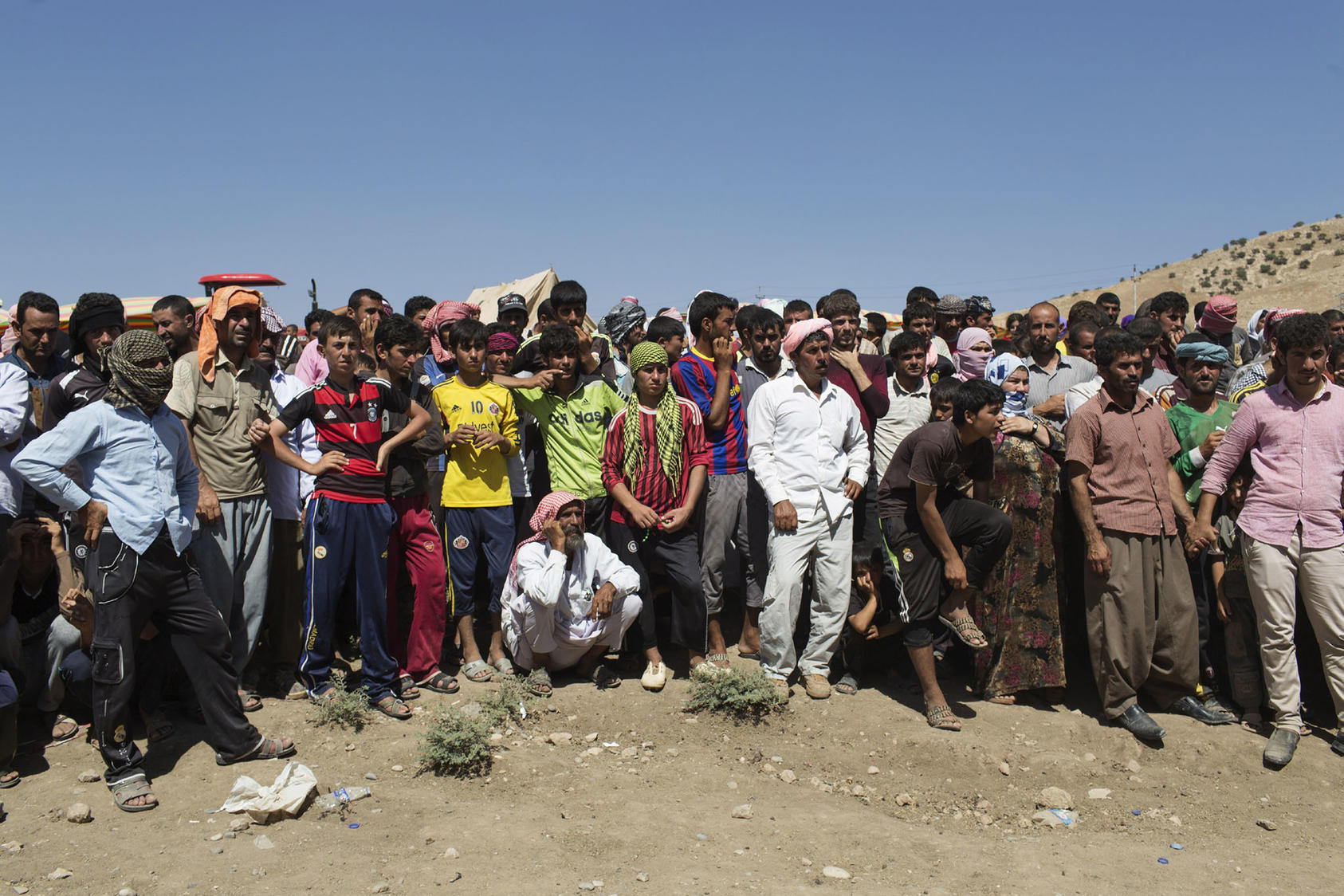 Iraqi Yazidi people wait to receive aid at a makeshift roadside camp near the border crossing in Feshkhabour, Dohuk Province, northern Iraq, Aug. 11, 2014.