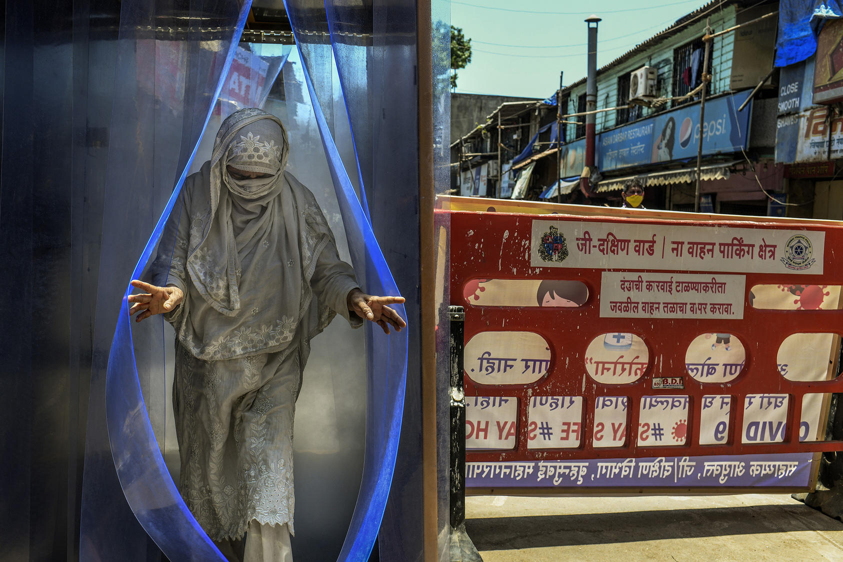 A woman passes through a sanitizing tunnel in Mumbai. April 25, 2020. (Atul Loke/The New York Times)
