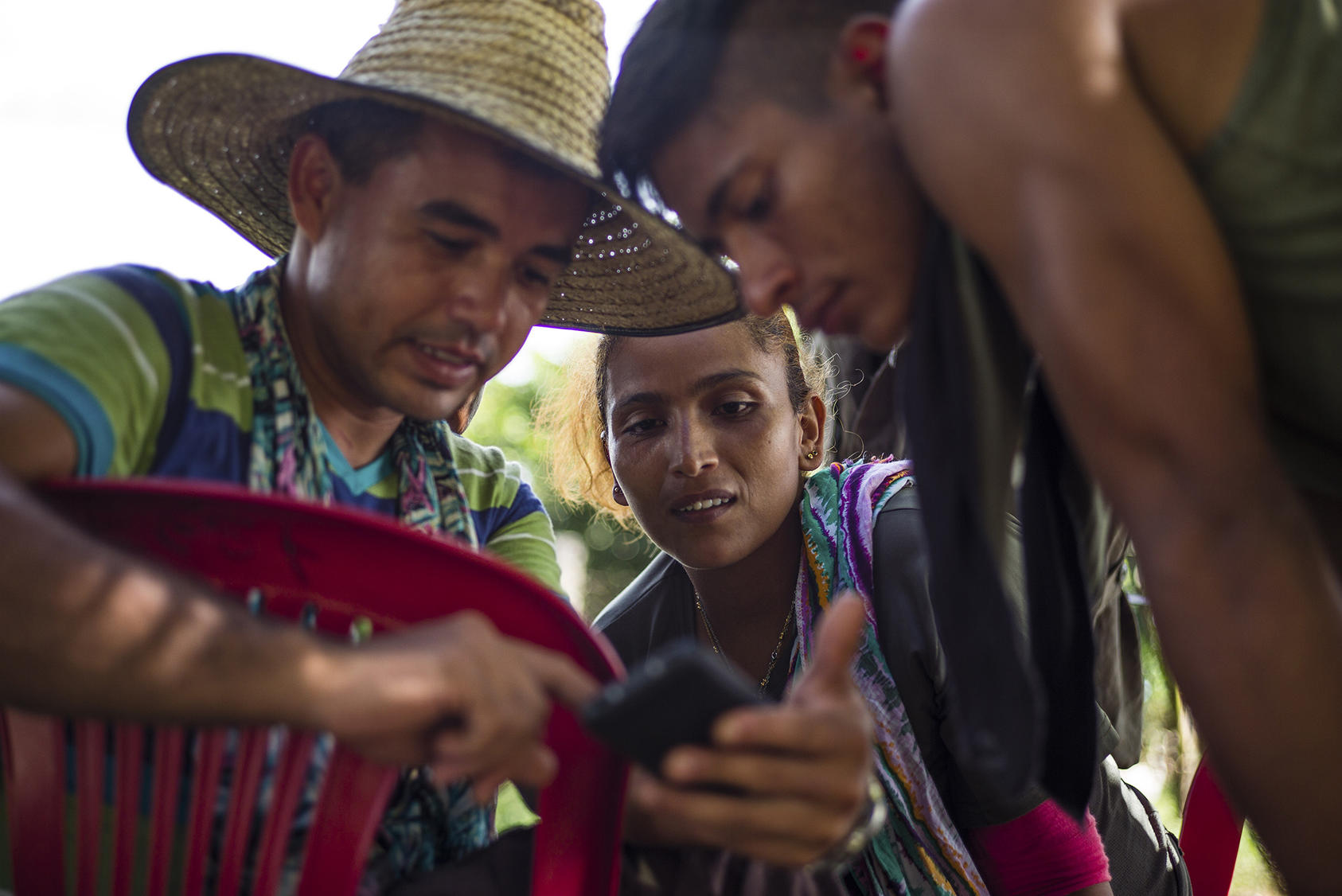 Members of the Revolutionary Armed Forces of Colombia look at photos on a mobile phone as they gathered on the eve of a historic armistice in San Vicente del Caguán on September 16, 2016. (Federico Rios Escobar/New York Times)