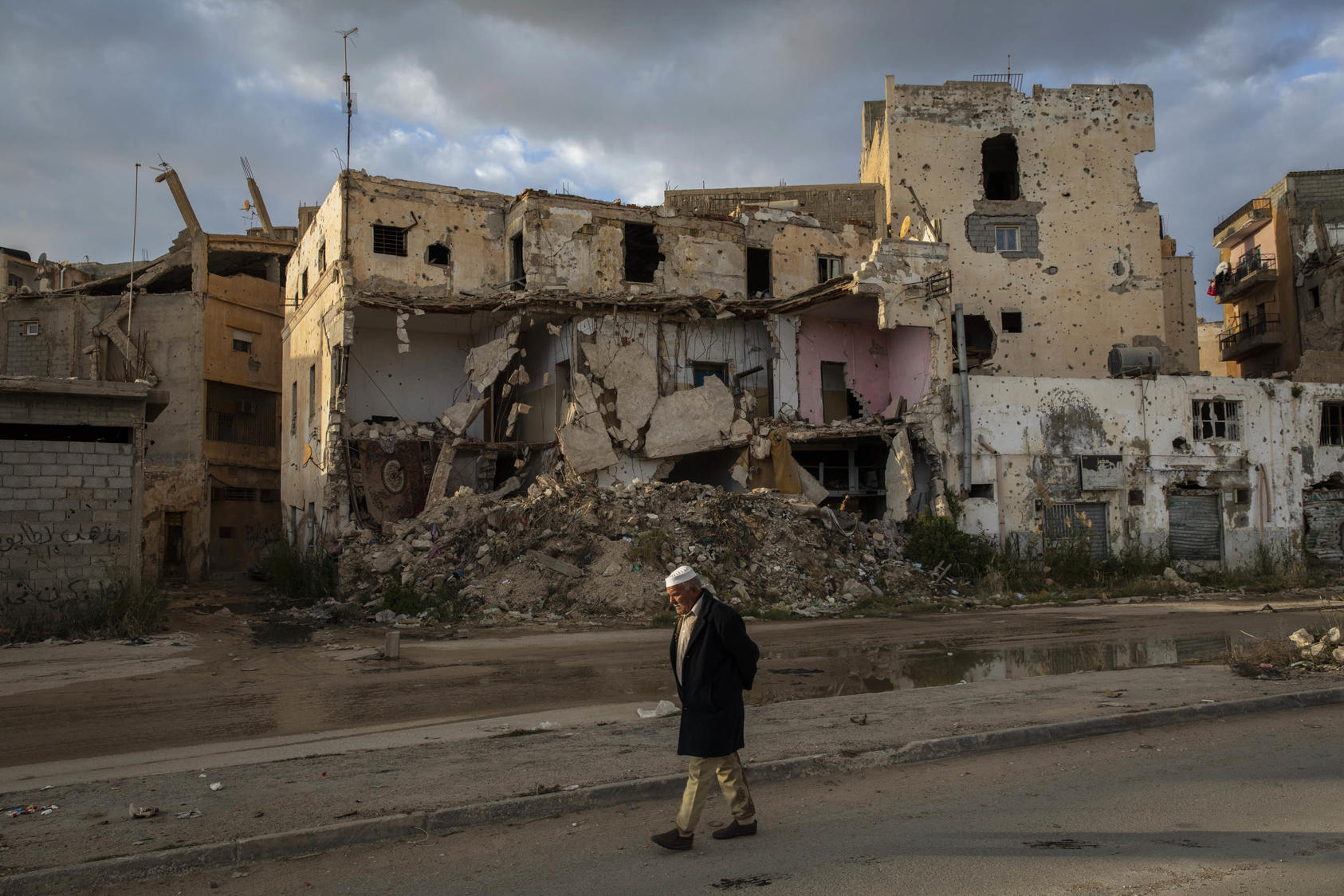 A man walks amid ruins in Benghazi. Fighting surged in 2020 as foreign governments increased support to allied factions in Libya. Peacebuilding efforts will require an end to such support—and dialogue among Libyans. (Ivor Prickett/The New York Times)