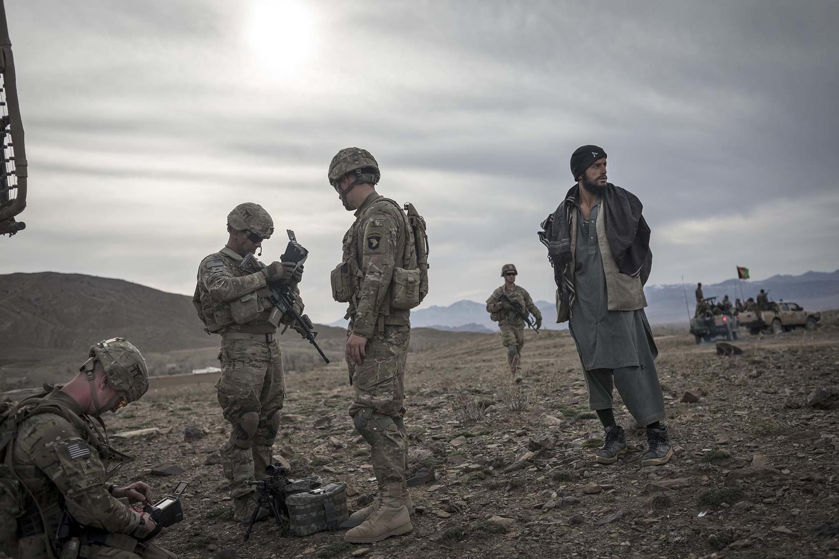 Soldiers from the 101st Airborne Division stand next to an Afghan suspected of Taliban connections in Lakaray, Afghanistan, April 14, 2013. (Sergey Ponomarev/The New York Times)