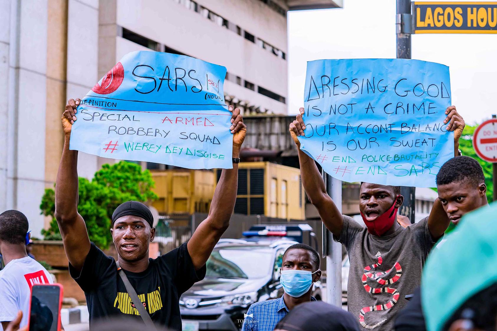 Nigerians in Lagos protest attacks and extortion against youth by the SARS police unit. “Dressing cool is not a crime,” a protester’s sign declares. (TobiJamesCandids/CC License 4.0)