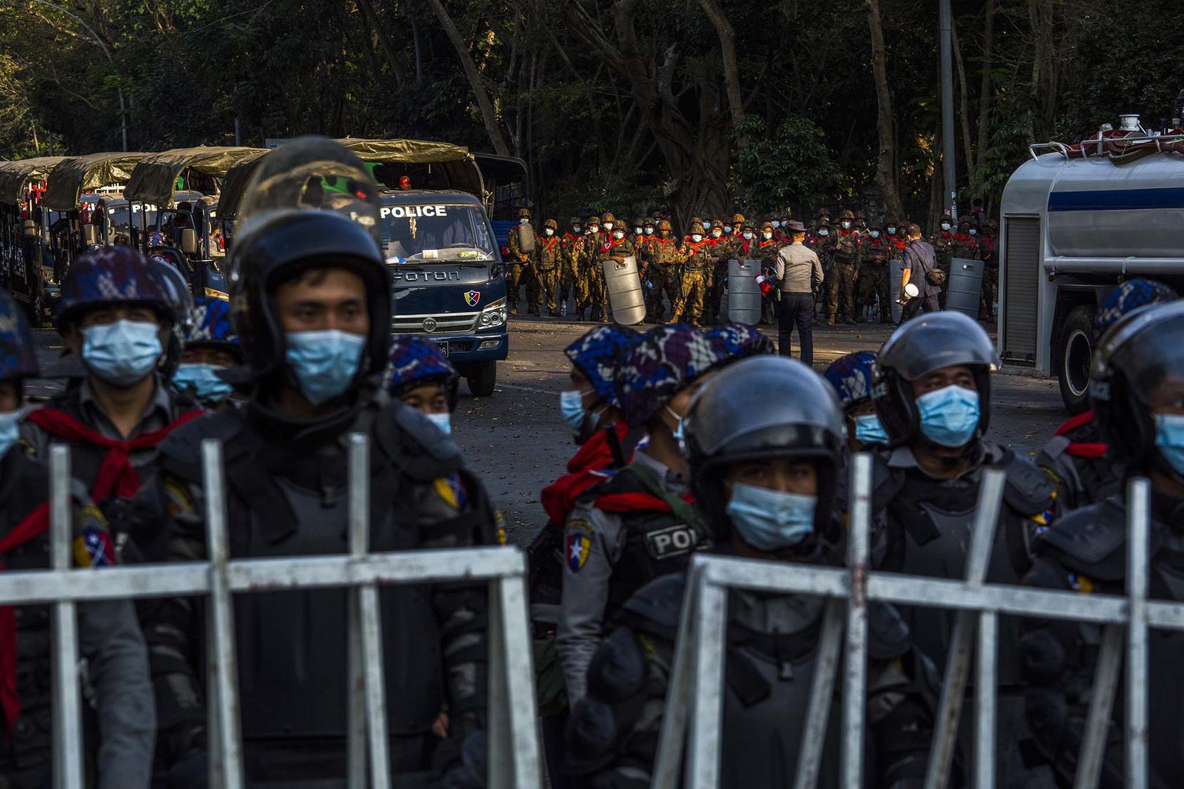Police and military forces stand by, as tens of thousands of people gather on University Avenue Road to protest against the military's seizure of power, Feb. 9, 2021, in Yangon, Myanmar. (The New York Times)