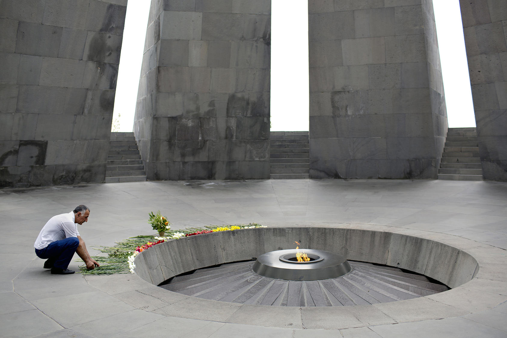 A man places flowers at the eternal flame in the Armenian Genocide memorial complex in Yerevan, Armenia, on Aug. 11, 2018. (Danielle Villasana/The New York Times)