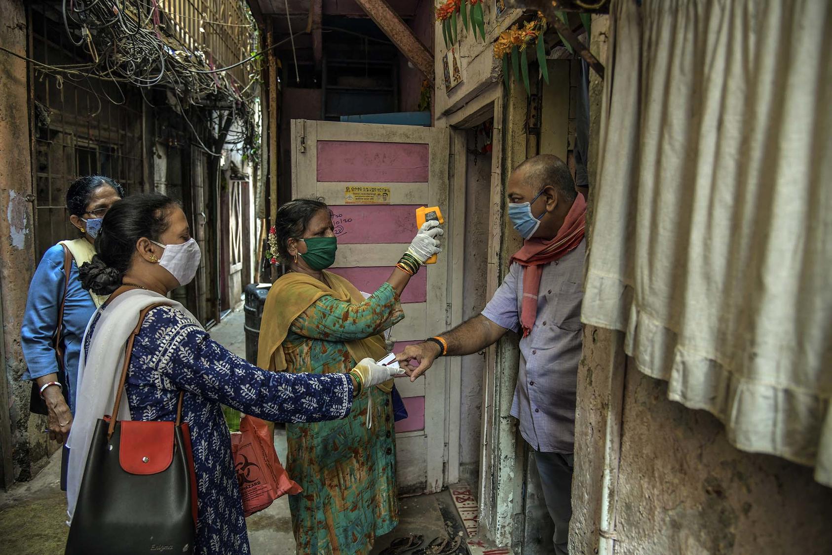 Health workers doing contact tracing check the body temperature and blood oxygen level of a man in Mumbai, India. April 15, 2021. (Atul Loke/The New York Times)
