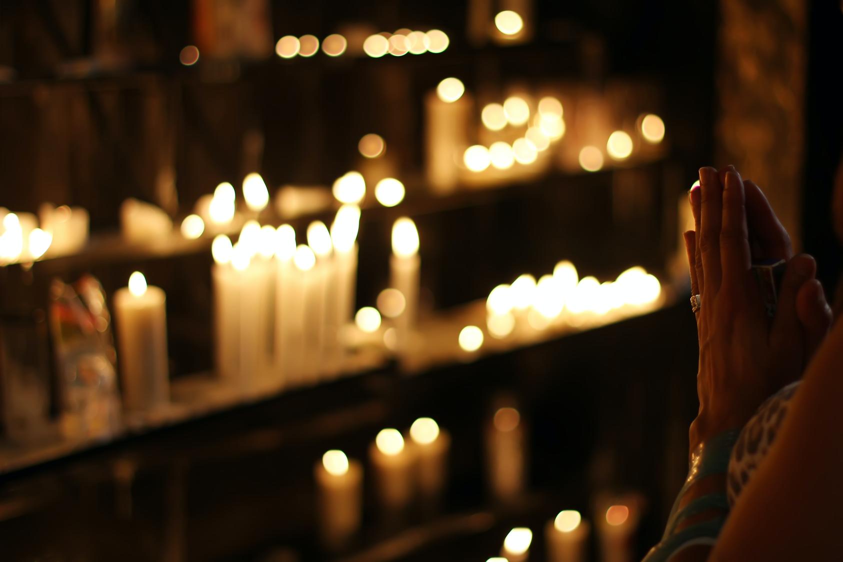A person worships near lit candles.