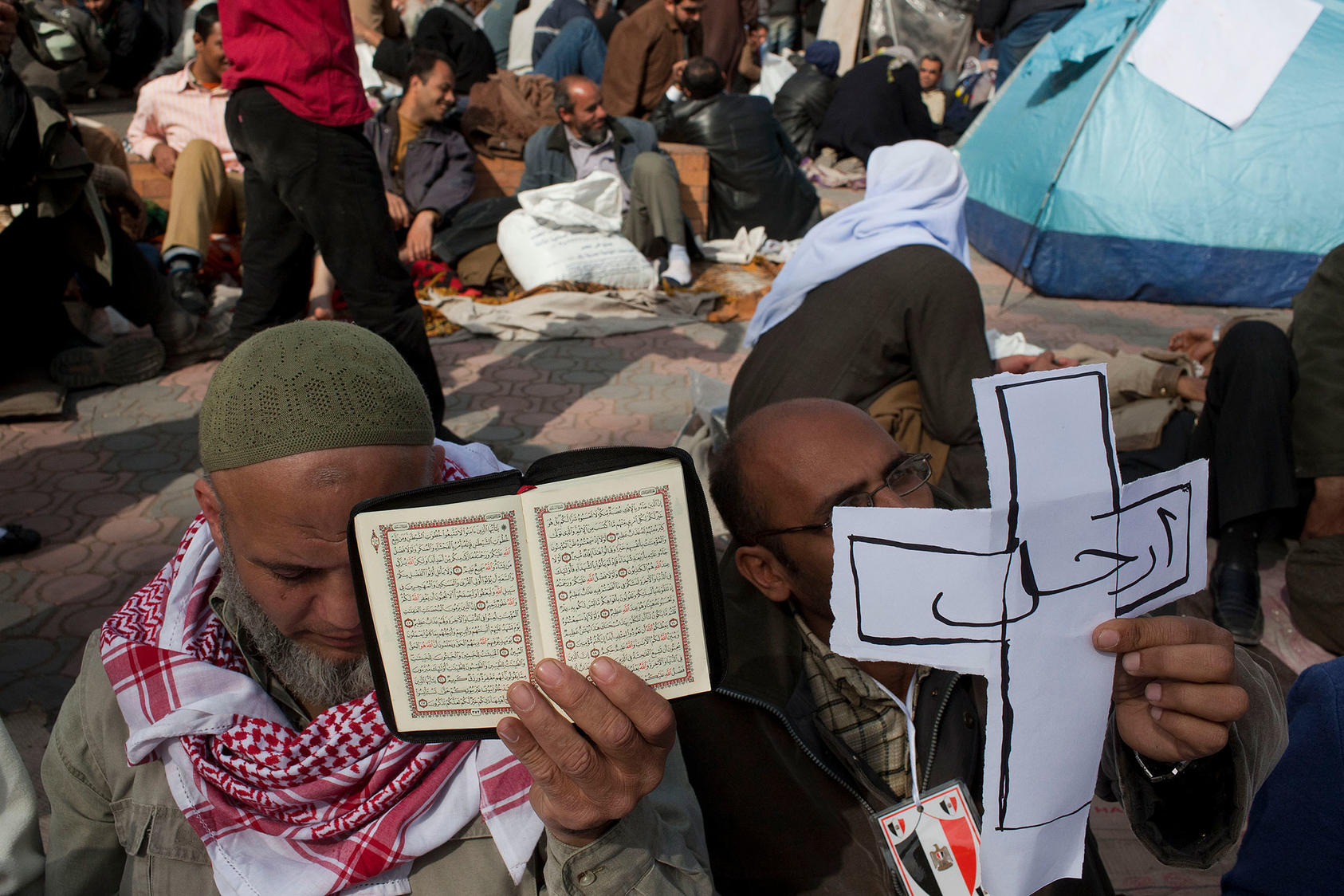 Protesters share a moment of Muslim and Christian unity as they sit nearby makeshift encampments during anti-government protests at Tahrir Square in Cairo. Feb. 6, 2011. (Scott Nelson/The New York Times)