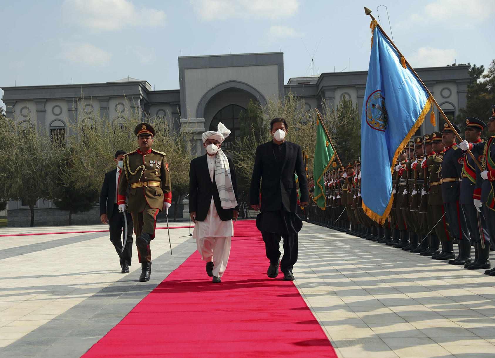 Afghan President Ashraf Ghani, center, and Pakistani Prime Minister Imran Khan, both wearing face masks because of the COVID-19 pandemic, inspect the honor guard before a news conference at the Presidential Palace in Kabul, Afghanistan, on November 19, 2020. (Rahmat Gul/AP)