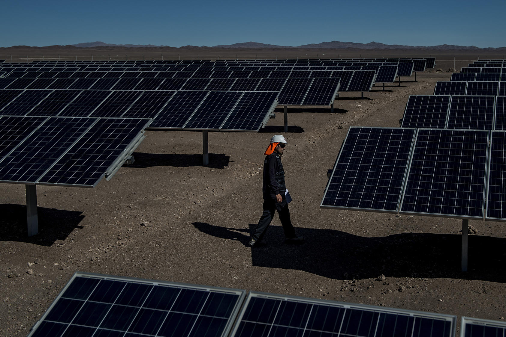 A worker inspects solar panels at a solar field in the Atacama Desert in Calama, Chile. June 21, 2017. (Meridith Kohut/The New York Times)