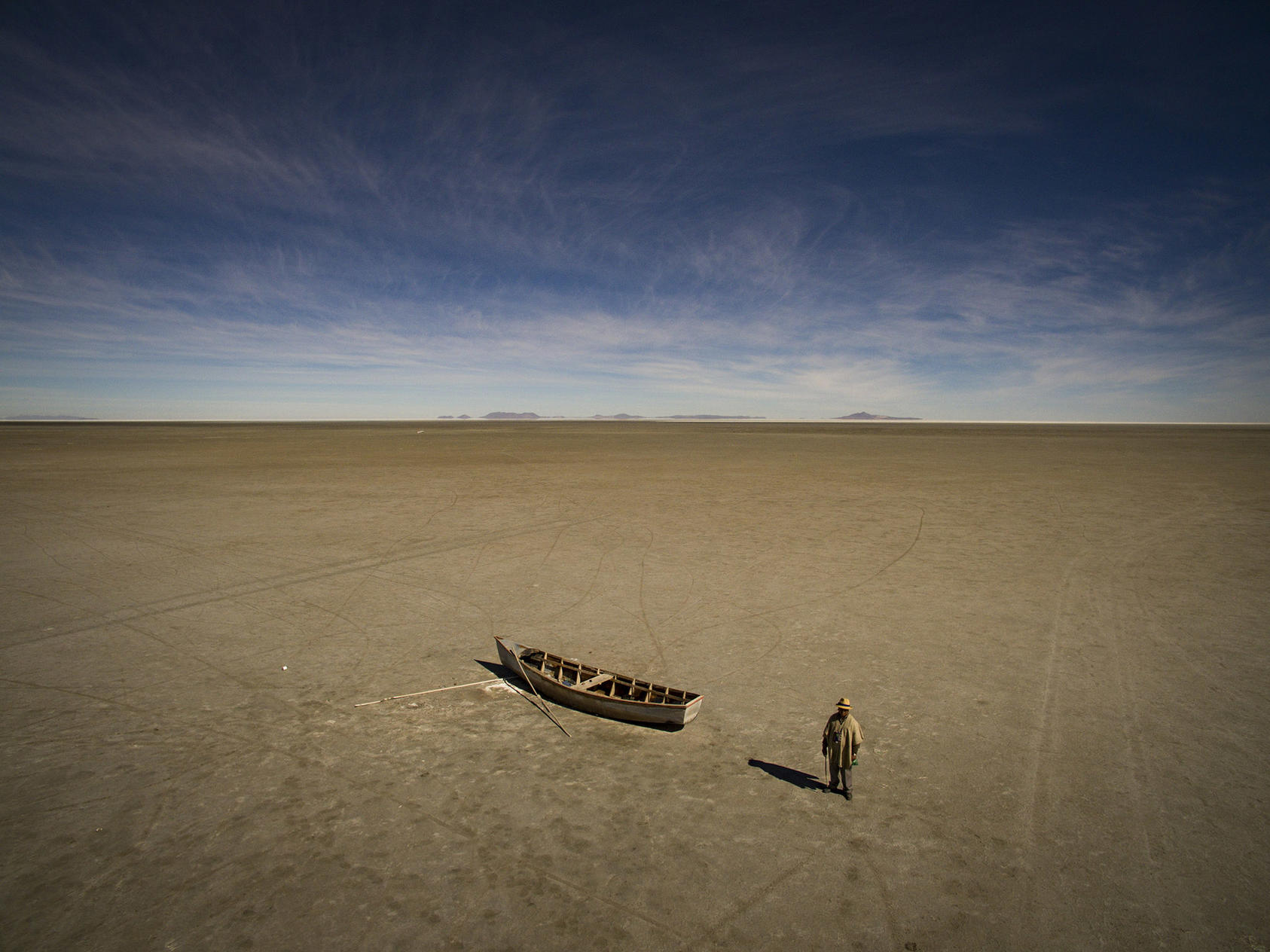 Felix Condoni, Llapallapani’s mayor and a former fisherman, with a boat in the dry bed of Lake Poopo outside of Llapallapani, Bolivia, May 1, 2016. Lake Poopo, once Bolivia’s second-largest, is now just a dry, salty expanse. Many of the Uru-Murato people, who had lived off its waters for generations, have left joining a new global march of refugees fleeing not war or persecution, but climate change. (Josh Haner/The New York Times) 