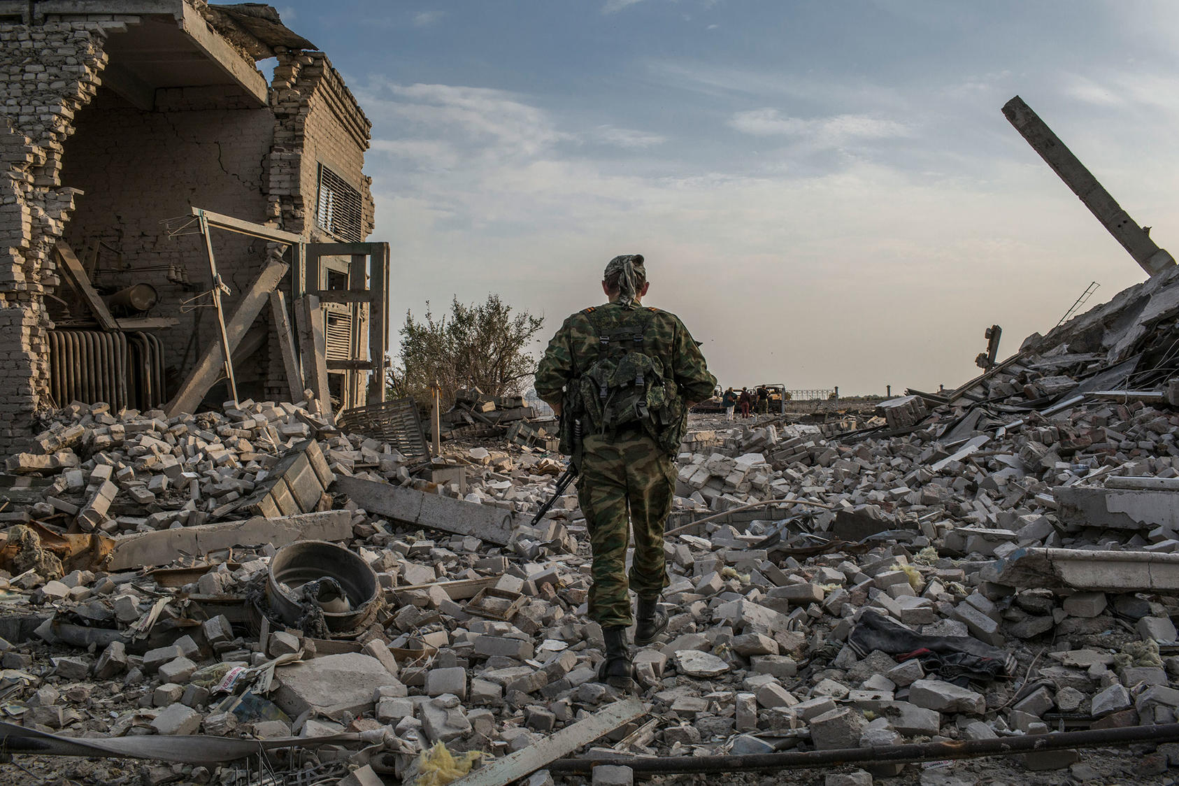 A fighter of Russian-backed forces strides through the rubble of the airport in Luhansk, Ukraine, in 2014. The war has killed 14,000 Ukrainians over eight years, and Russian forces are massed anew on the border. (Mauricio Lima/The New York Times)
