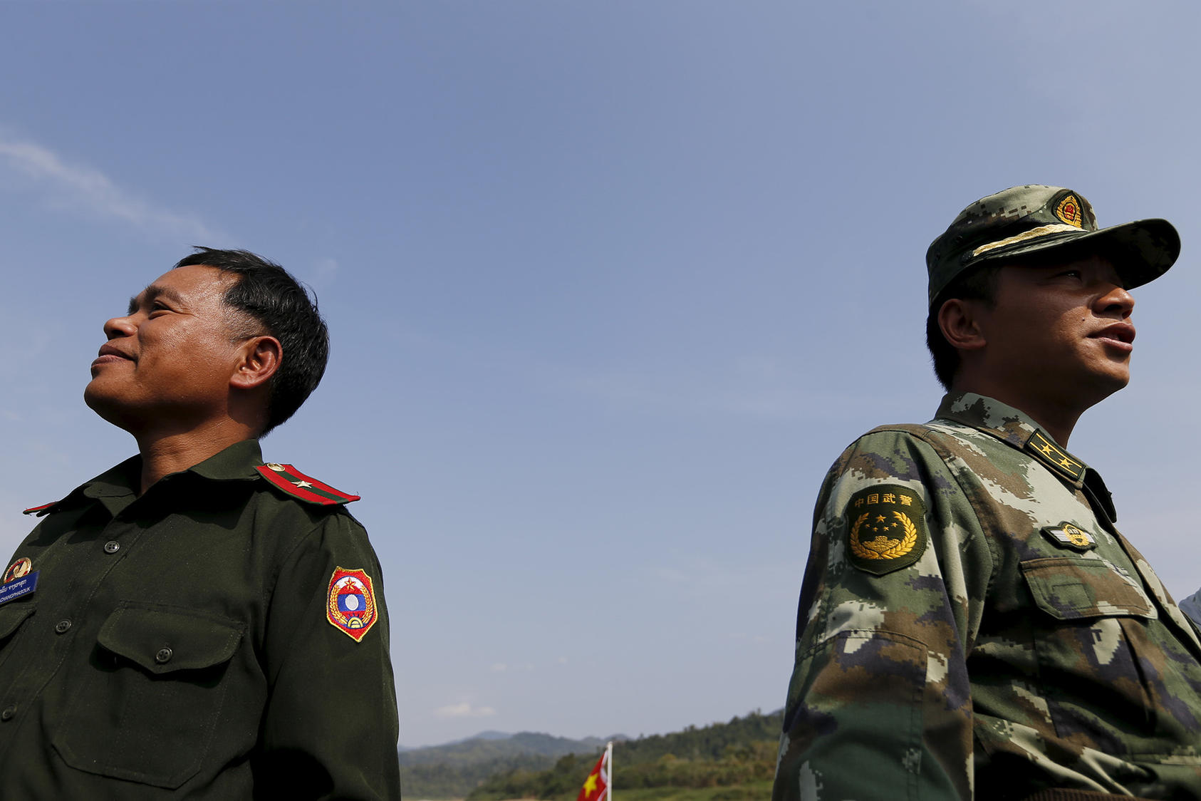 A soldier from Laos and a Chinese paramilitary police officer stand at an army post on the Mekong River on March 1, 2016. (Jorge Silva/Reuters)