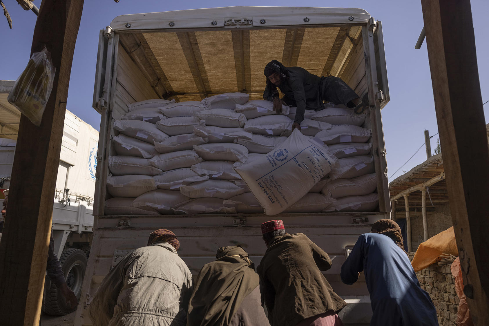 Sacks of flour from a World Food Program convoy are unloaded in Afghanistan. Oct. 27, 2021. (Victor J. Blue/The New York Times)