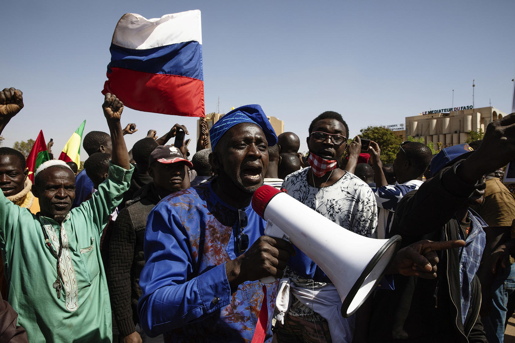 Men support Burkina Faso’s January coup with a Russian flag—a jab at France amid anger at insecurity under the prior civilian government, backed by French forces. Most Burkinabe citizens reject coups in research surveys. (Malin Fezehai/The New York Times)