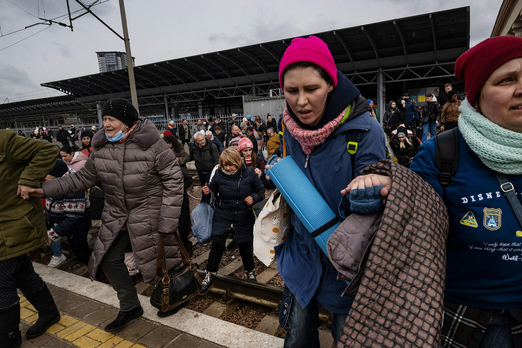 Families rush across train tracks to get to the next train heading west toward Lviv at the main train station in Kyiv, March 4, 2022. (Lynsey Addario/The New York Times)