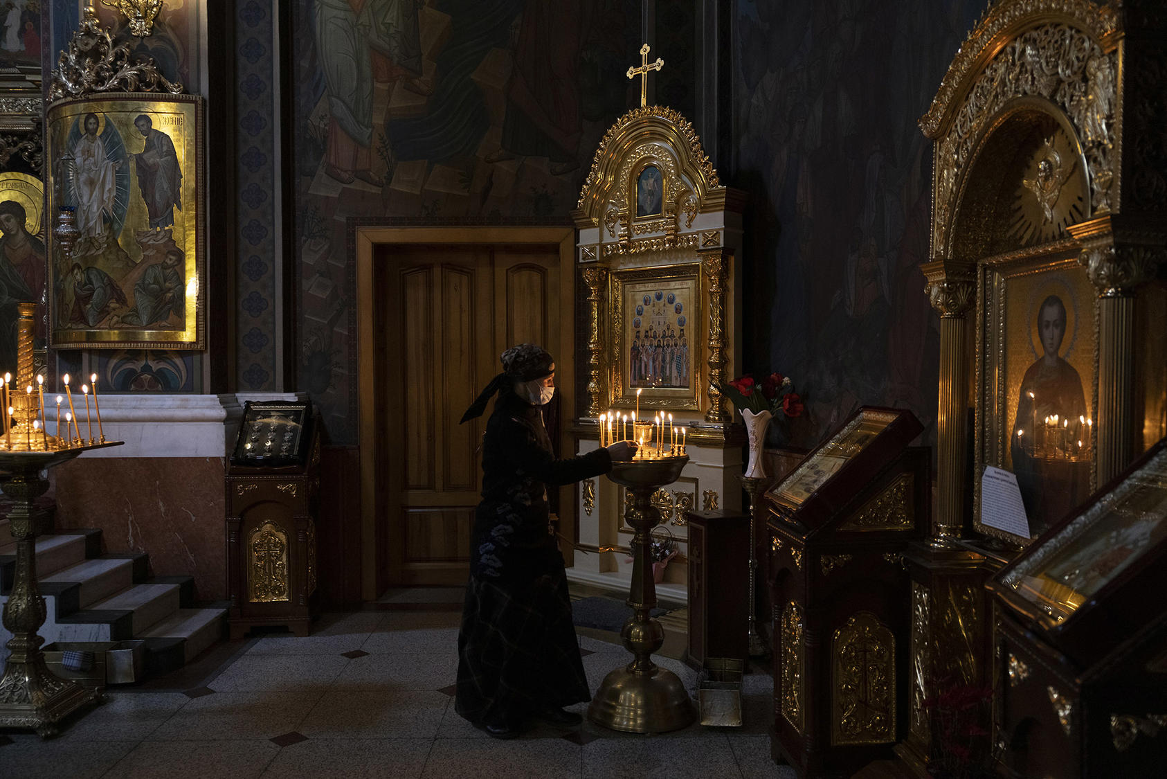 A woman lights a candle at the Holy Transfiguration Cathedral in Vinnytsia, Ukraine. March 12, 2022. (Ivor Prickett/The New York Times)