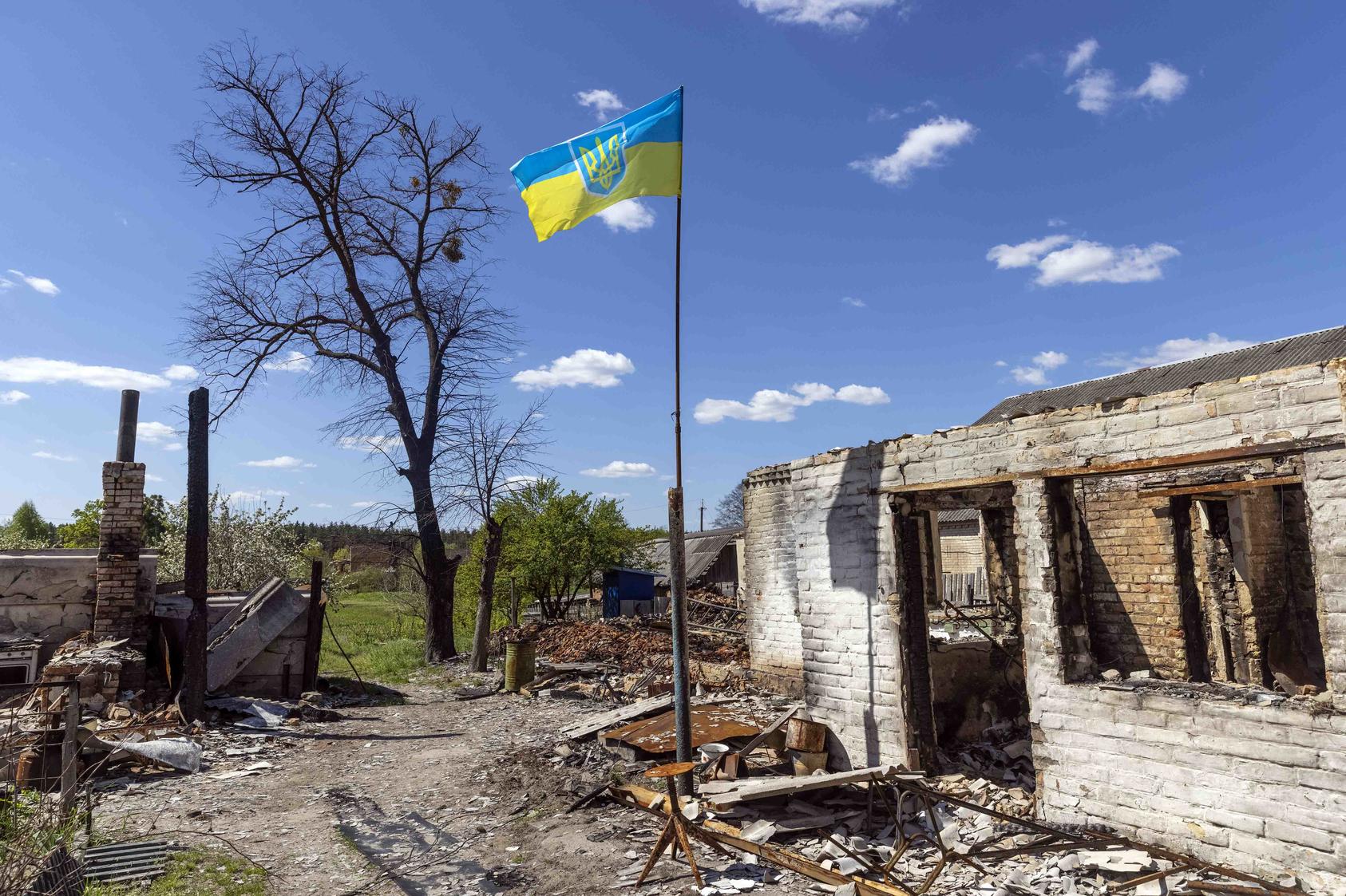 The flag of Ukraine flies over the wreckage of a home in the village of Moschun, north of Kyiv, on Tuesday, May 10, 2022. Kersti Kaljulaid, a former president of Estonia, wants the West to enhance its support for Ukraine.  (David Guttenfelder/The New York Times)