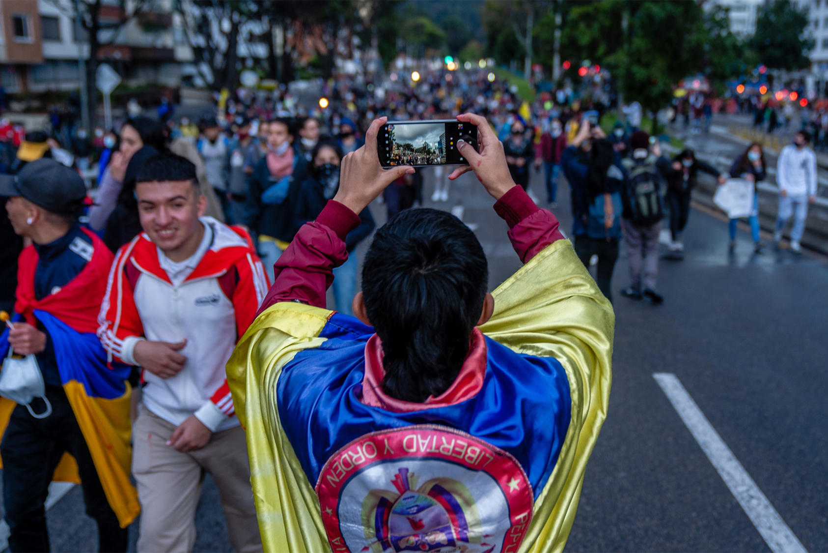 A demonstrator uses his smartphone to capture a protest march in Bogotá, Colombia. May 4, 2021. (Federico Rios/The New York Times)