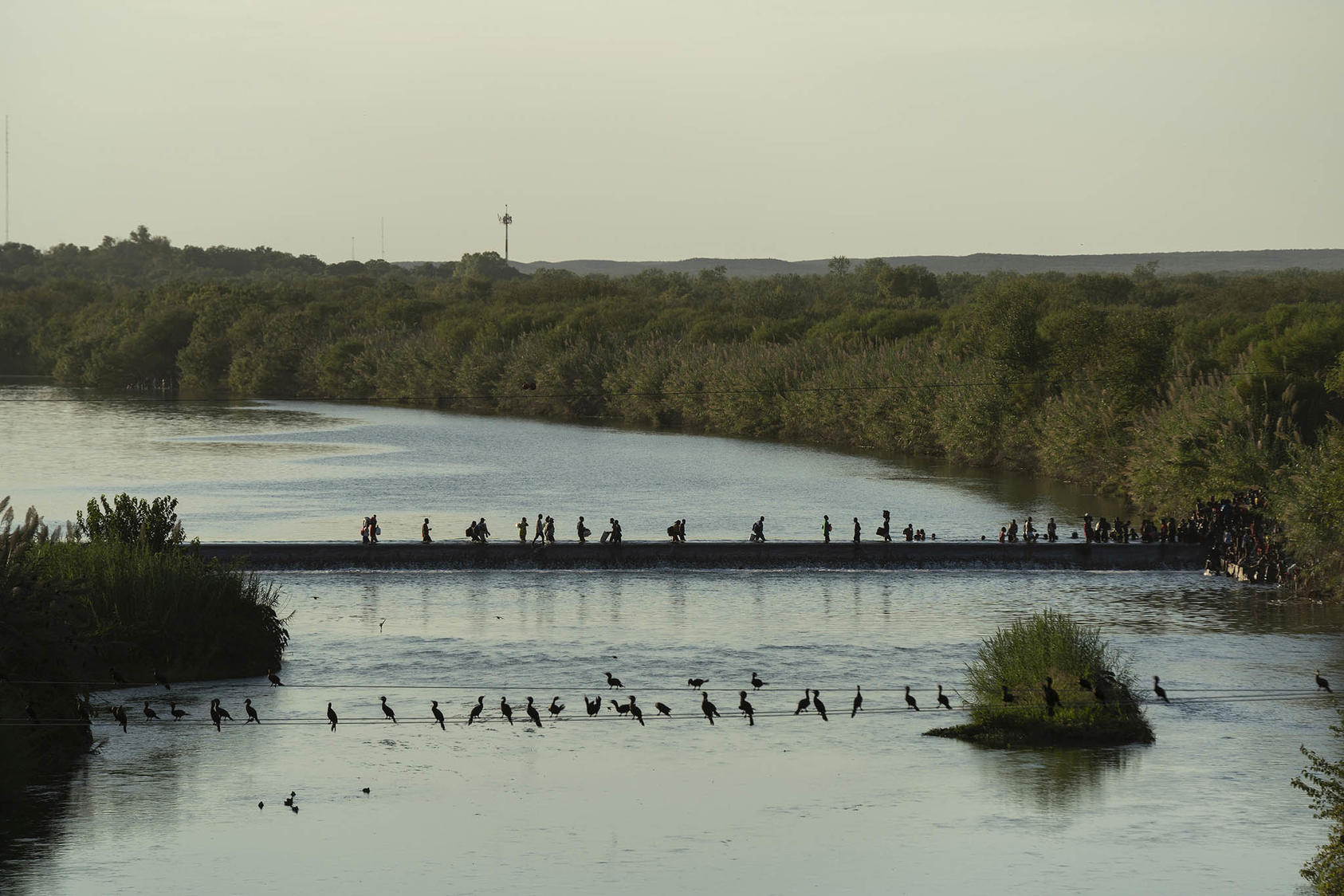 People are seen crossing back and forth between Mexico, left, and the U.S., in Del Rio, Texas on Sept. 16, 2021.(Verónica G. Cárdenas/The New York Times)