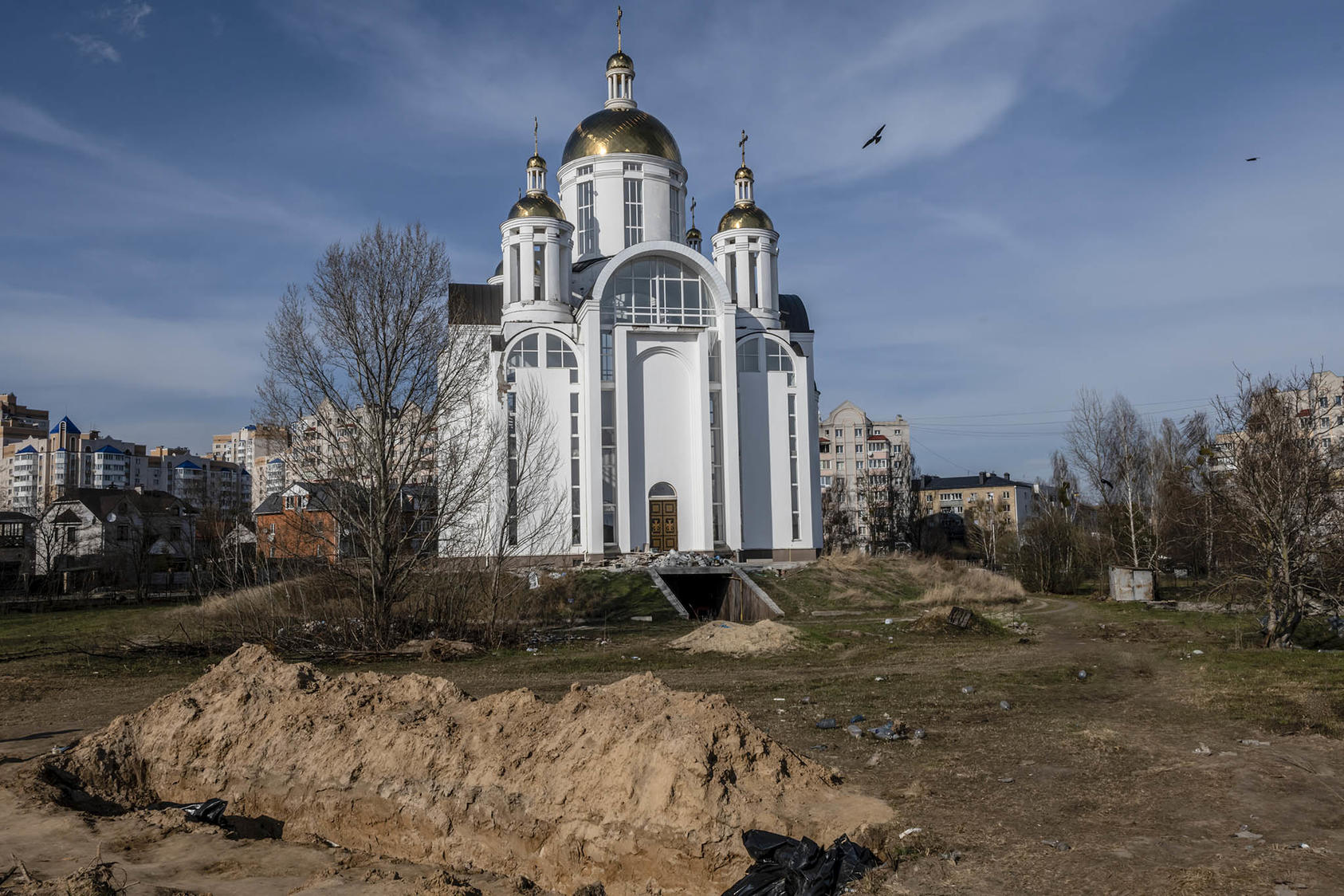 A mass grave on the grounds of the Church of St. Andrews in Bucha, Ukraine, April 7, 2022. (Daniel Berehulak/The New York Times)