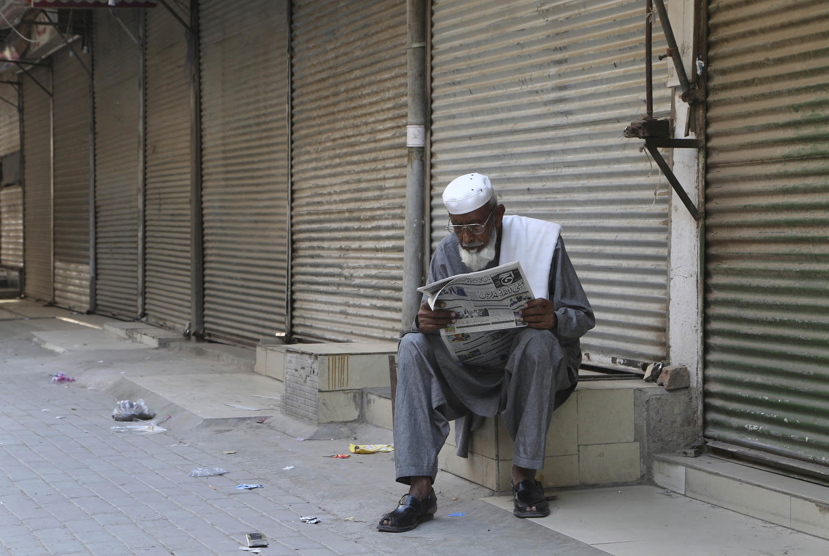A man reads a morning newspaper at a market closed due to government COVID-19 restrictions in Peshawar, Pakistan, on May 1, 2021. (Photo by Muhammad Sajjad/AP)