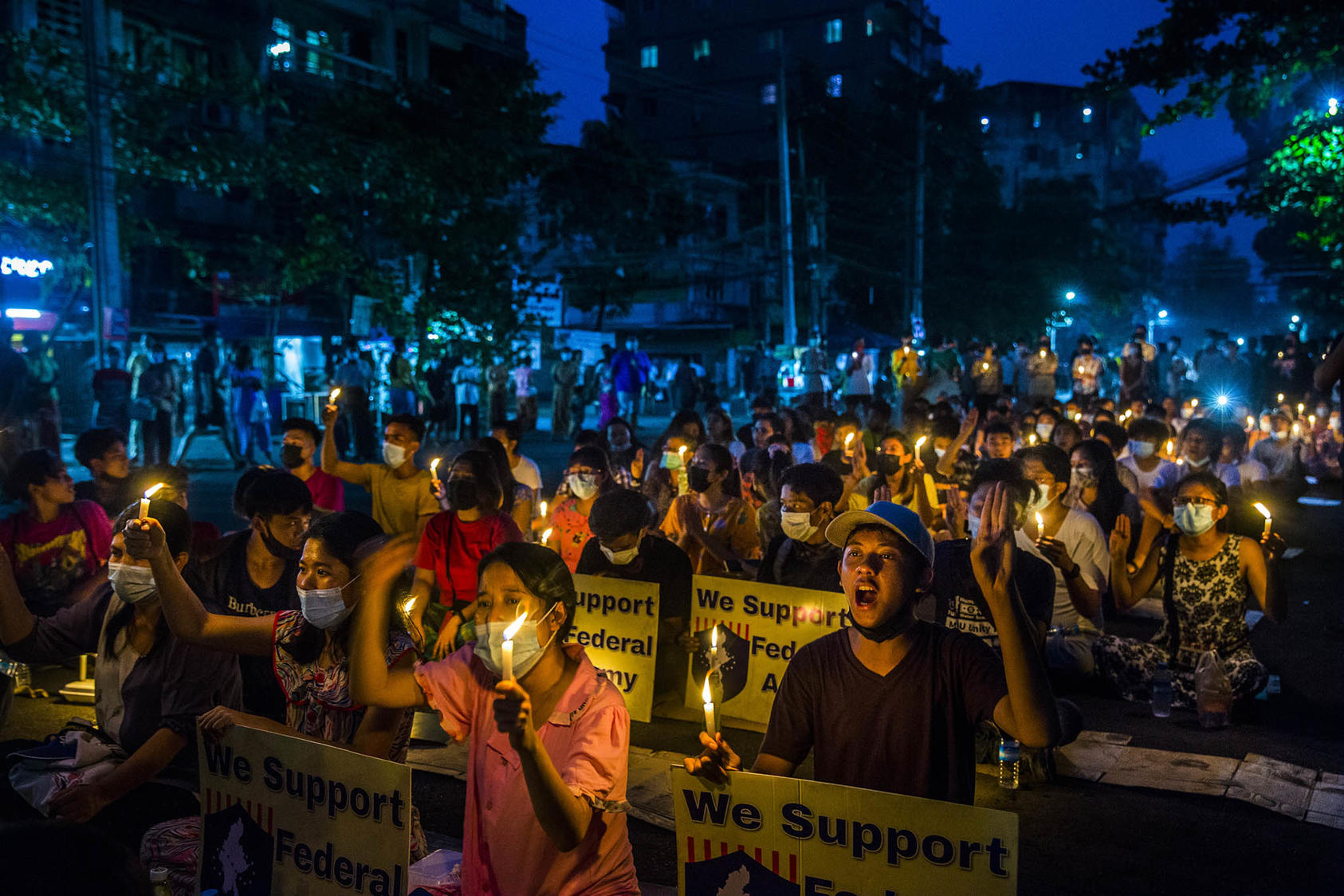 Anti-coup demonstrators, many with signs showing support for a civilian-formed federal army, hold candles and sing protest songs as they sit in the streets of Yangon, Myanmar, on Saturday, April 3, 2021. (The New York Times)