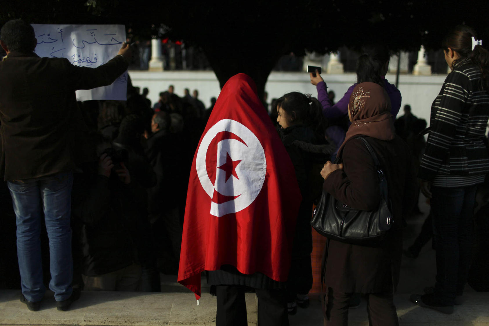 A woman wears a Tunisian flag during a protest outside a government building in Tunis, Tunisia. January 21, 2011. (Holly Pickett/The New York Times)
