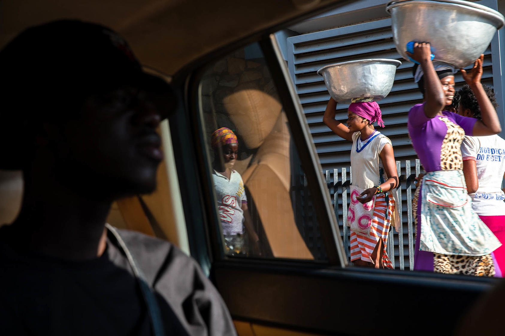 Young women, who balance large bowls on their heads, are paid to carry other people’s shopping bundles in the open-air Makola Market in Accra, Ghana, on November 23, 2019. (Photo by Francis Kokoroko/New York Times)