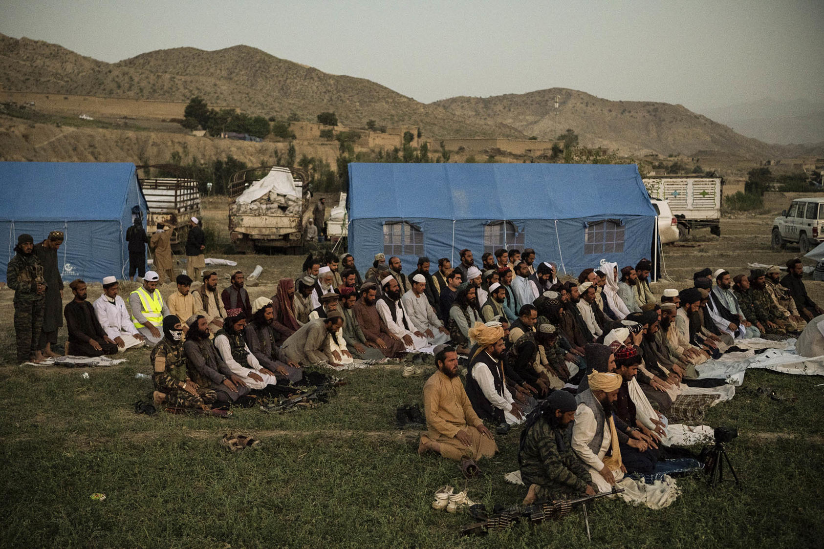 Taliban officials pray before distributing relief supplies in the Geyun district of Paktika Province, Afghanistan on June 23, 2022. (Kiana Hayeri/The New York Times)