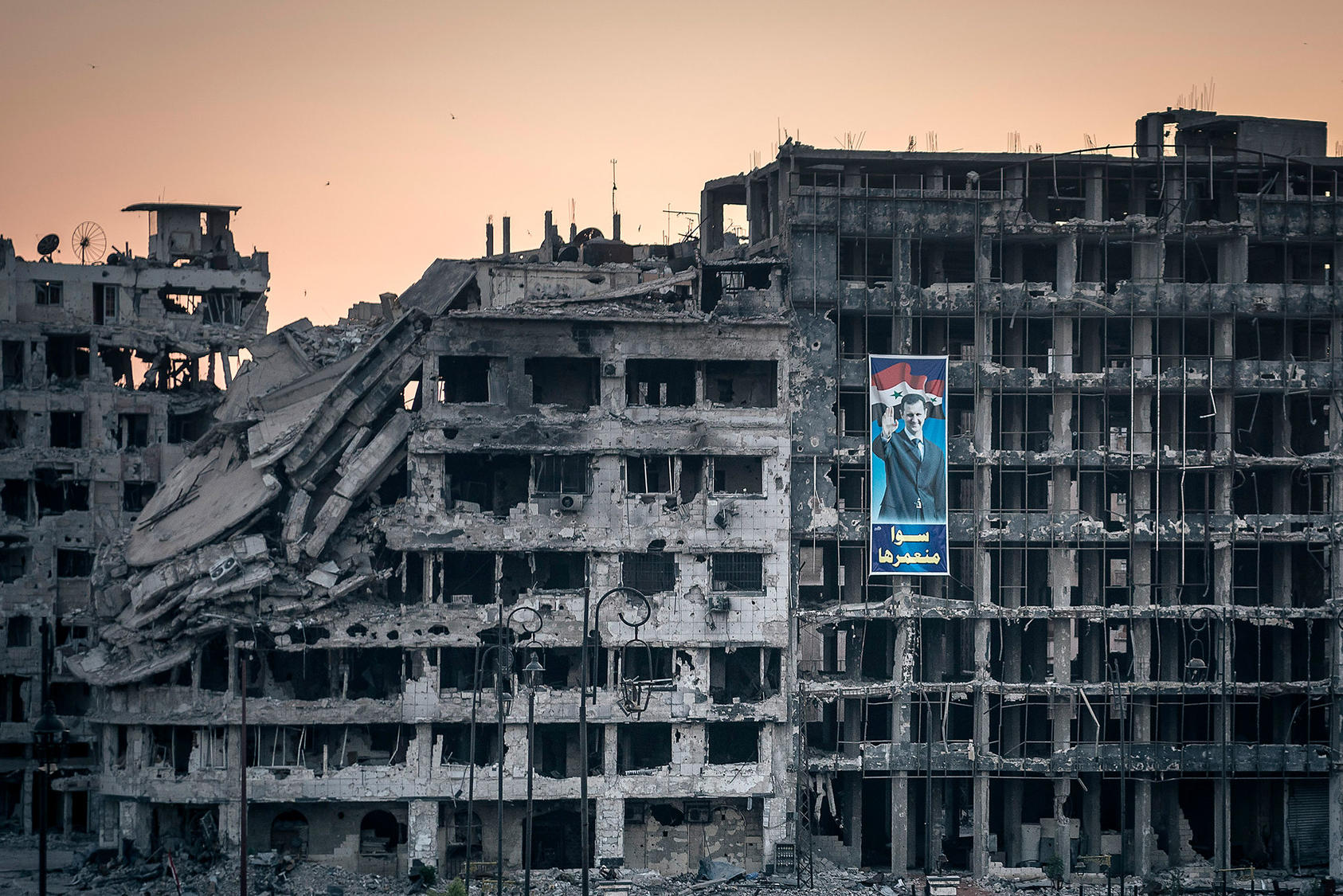 A campaign poster for President Bashar Assad hangs on a destroyed shopping mall in Homs, Syria, June 15, 2014. (Sergey Ponomarev/The New York Times)
