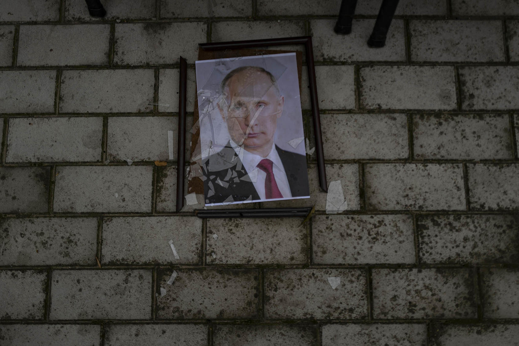 A smashed portrait of Russian President Vladimir Putin lies outside a police prison used to hold and torture Ukrainian prisoners by Russian forces in Kherson, Ukraine on Nov. 17, 2022. (Lynsey Addario/The New York Times)