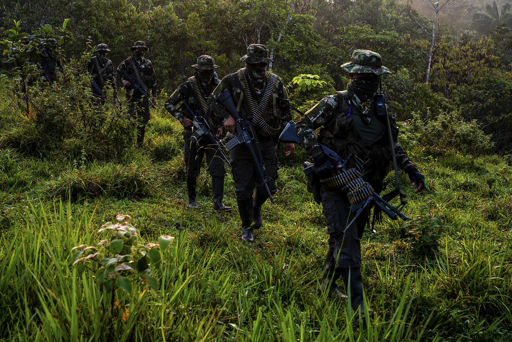 Masked fighters of a militia called Border Command move through jungle terrain last year. The group rejected Colombia’s 2016 peace accord and reportedly traffics drugs along Colombia’s southern borders. (Federico Rios/The New York Times)