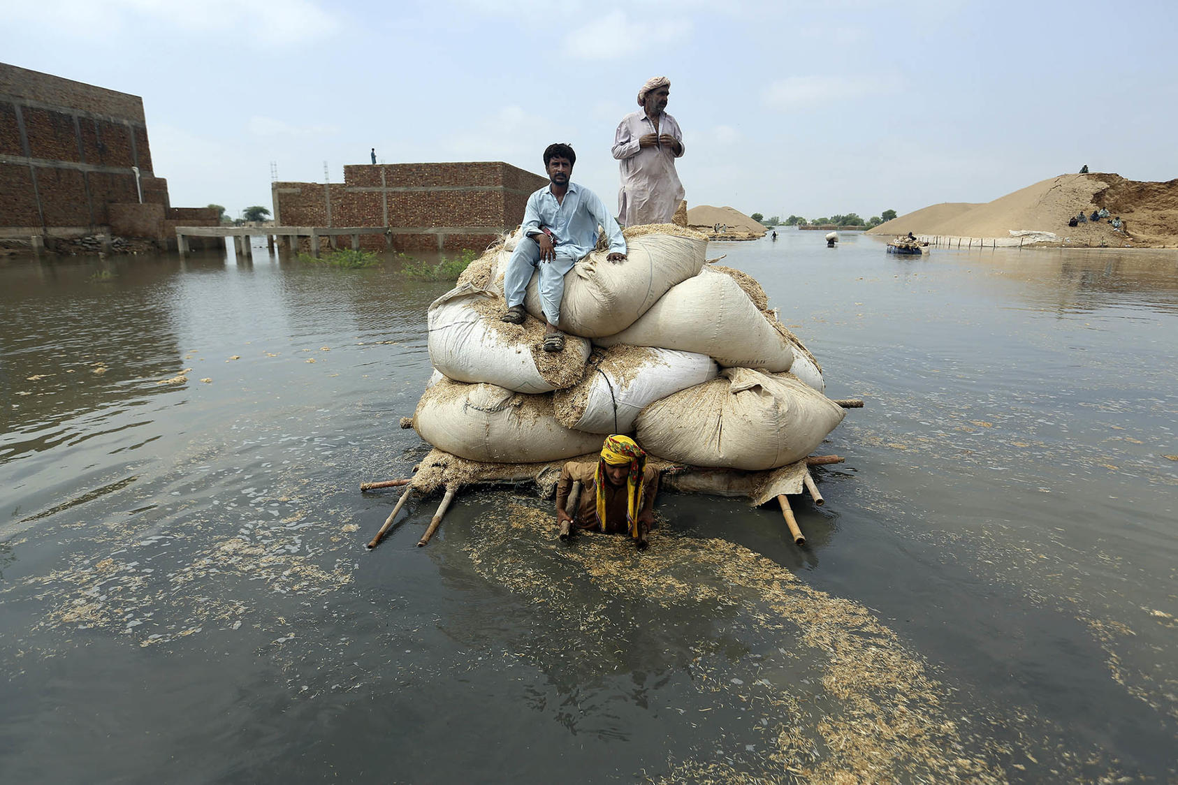 Victims of flooding from torrential monsoon rains use a makeshift barge to carry hay for cattle in Jafarabad, Pakistan, on September 5, 2022. (Photo by Fareed Khan/AP)