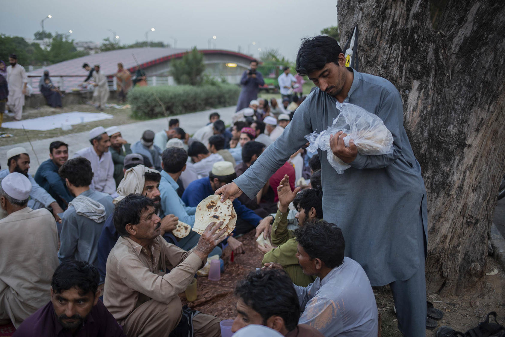 Volunteers distribute bread for people to break their fast during the Muslim holy month of Ramadan in Islamabad, Pakistan, on April 15, 2023. (Saiyna Bashir/The New York Times)