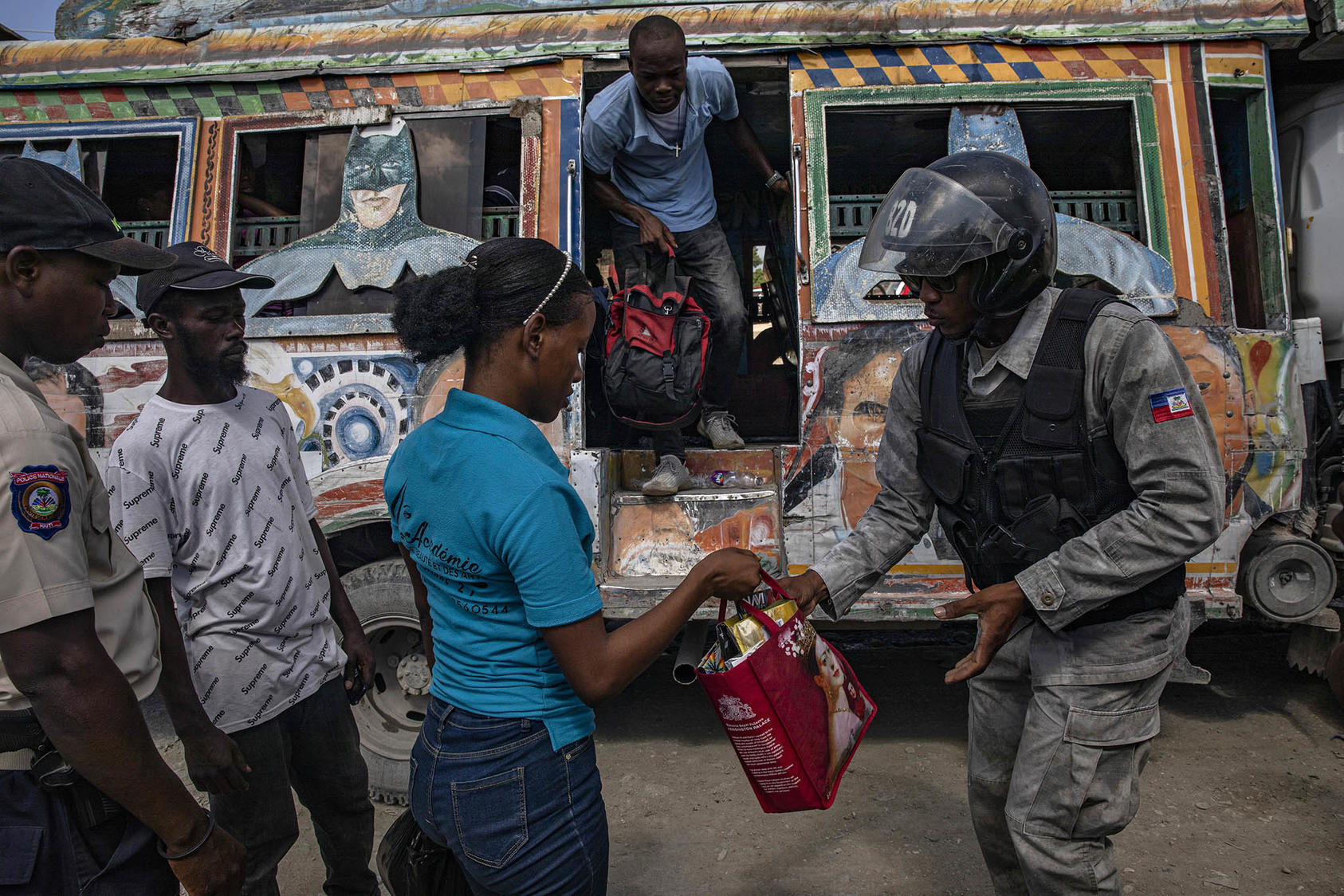 Les passagers de l'autobus passent par un point de contrôle de la police à Port-au-Prince, Haïti, près de l'entrée d'une zone de la capitale haïtienne contrôlée par le gang 400 Mawozo. 20 octobre 2021. (Adriana Zehbrauskas/The New York Times)