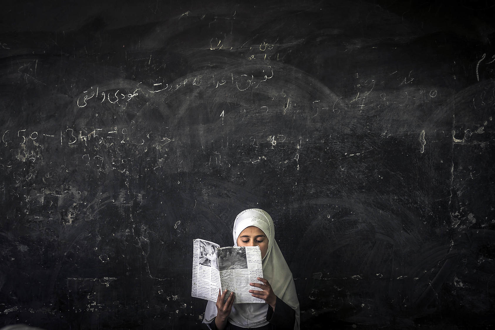 An Afghan girl reads in front of her class at a school in Chahankal, Afghanistan. April 11, 2013. (Sergey Ponomarev/The New York Times)