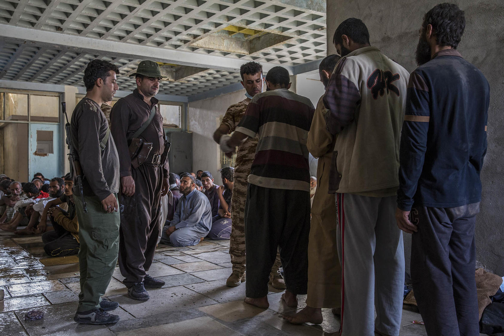 Men suspected of being Islamic State fighters are searched at a security screening center near Kirkuk, Iraq. October 1, 2017. (Ivor Prickett/The New York Times)