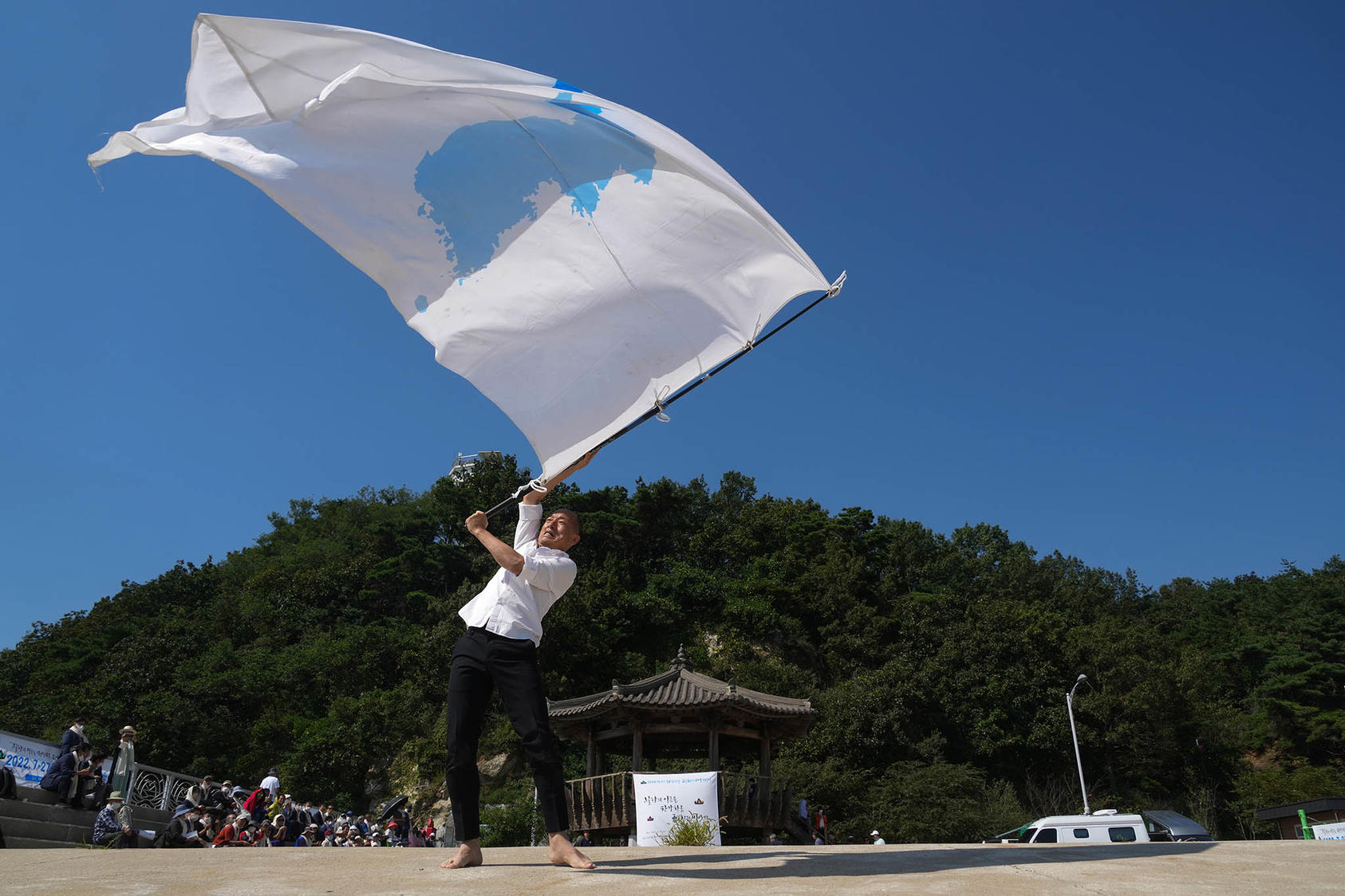 Lee San Hun dances with a flag that symbolizes a unified Korean Peninsula to mark the Korean War armistice anniversary in Ganghwa-do, South Korea, on September 21, 2022. (Chang W. Lee/The New York Times)