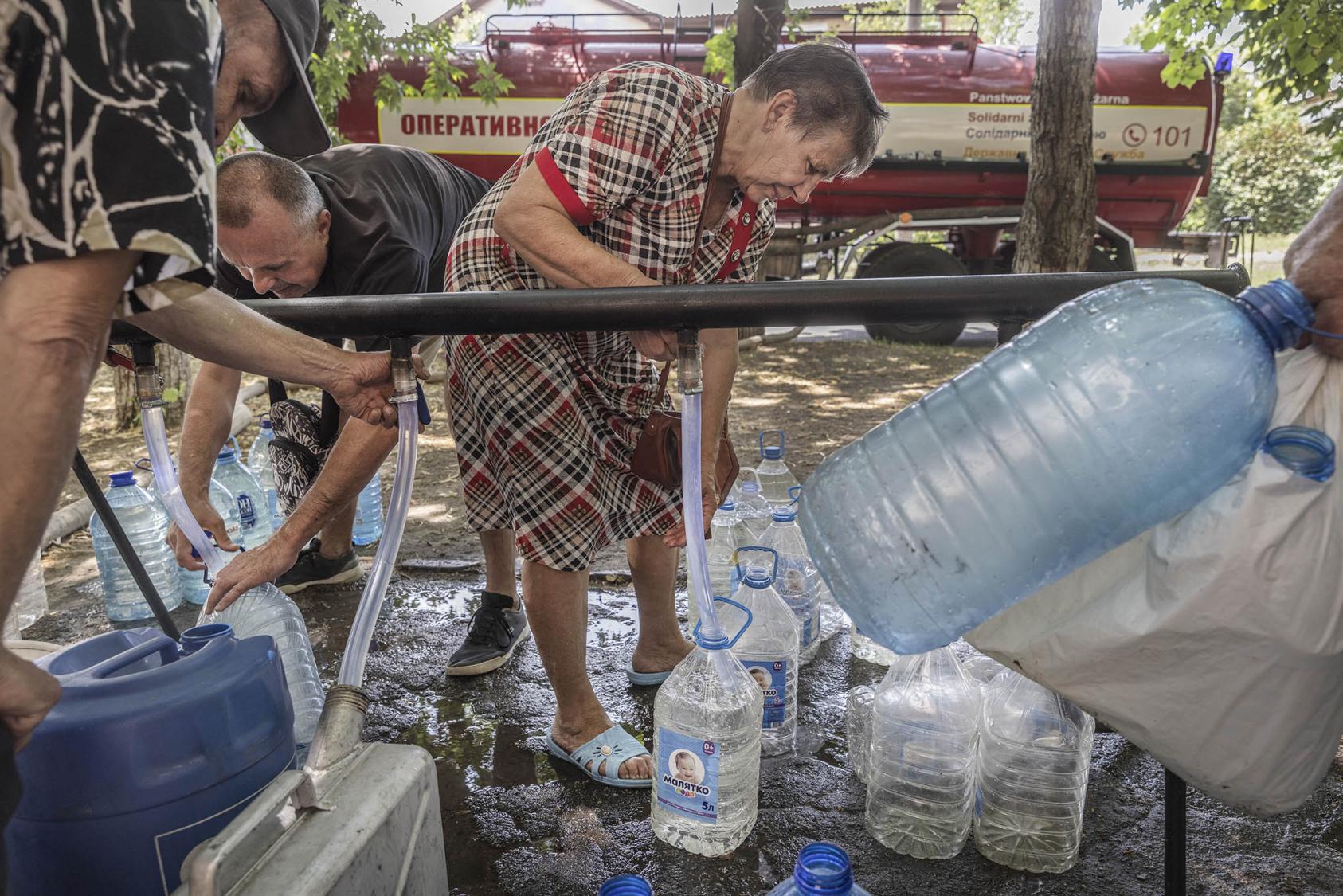 Residents collect drinking water at one of many water distribution points set up in the town of Nikopol, Ukraine. June 23, 2023. (David Guttenfelder/The New York Times)