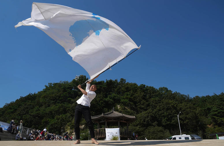 Lee San Hun dances with a flag that symbolizes a unified Korean Peninsula to mark the Korean War armistice anniversary in Ganghwa-do, South Korea, on September 21, 2022. (Chang W. Lee/The New York Times)